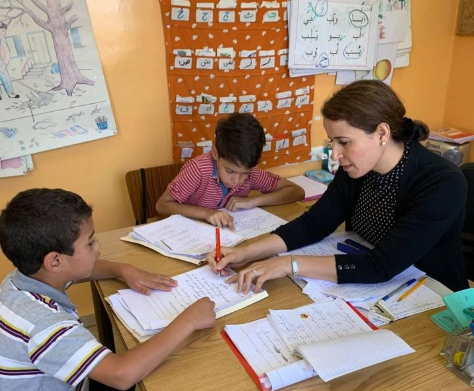 Teacher and two students around desk